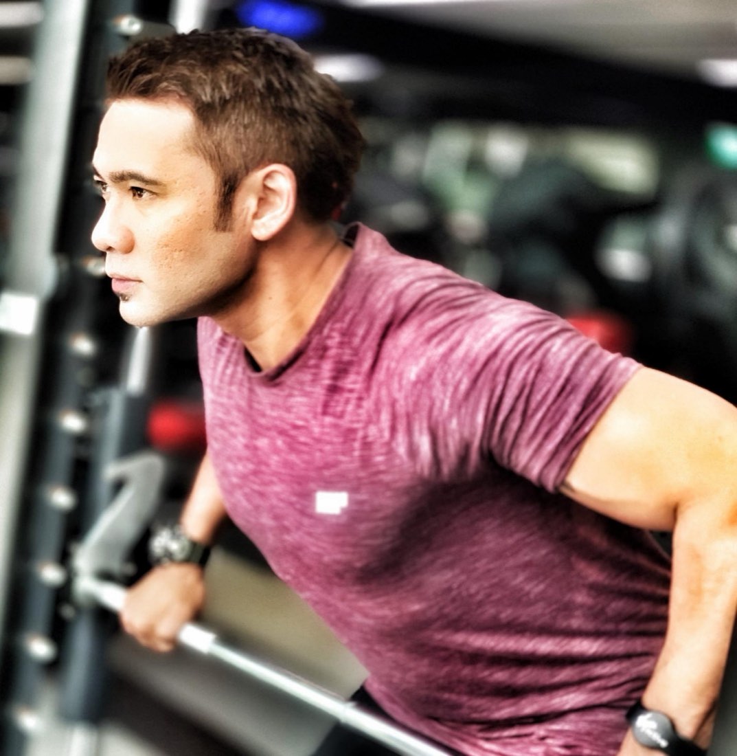 Rudy Rahman in side profile, mid-training, demonstrating a controlled strength movement.